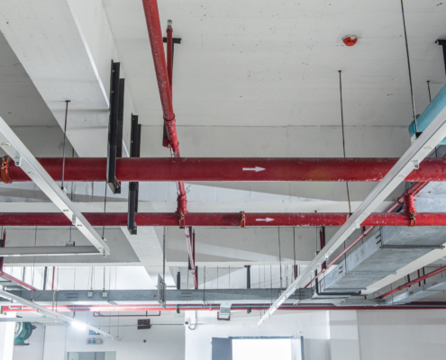 Fire protection sprinkler system with red pipes is placed to hanging from the ceiling