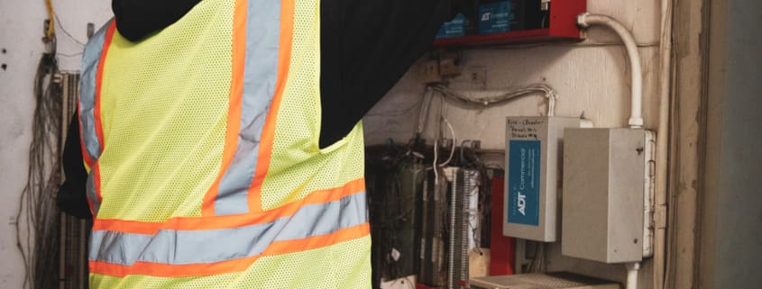 A man in a safety vest working on an electrical panel