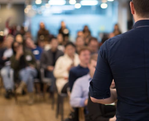 Speaker addressing group. Businessman entrepreneur giving a lecture to a sold-out crowd in a lecture hall. Speaker talking in seminar. Speaker at business conference or presentation stock photo. Male CEO talking during a business presentation in a board room. Copy space. Business coach concept.