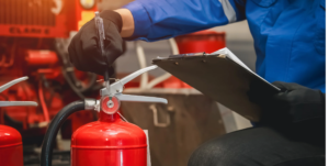Technician checking fire extinguisher pressure and condition in a fire control room